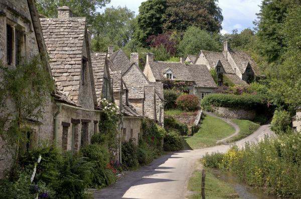 A row of cottages in Cirencester in the UK with grass and trees lining the road