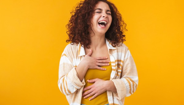 A woman laughing at some funny English slang words infront of a yellow background