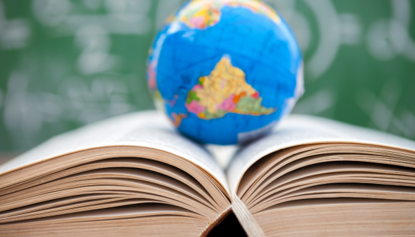 A small globe sitting on top of a book showing English is important for education