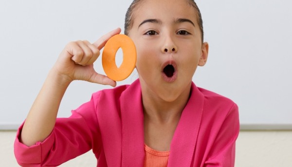 a little girl holding the letter o and making an o shape with her mouth to improve english pronunciation