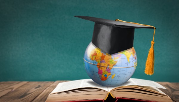 globe on top of a book with a graduation cap representing study english abroad