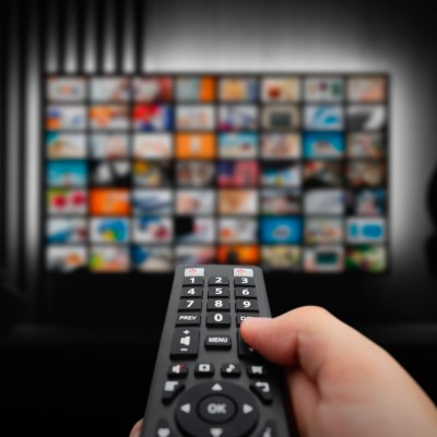 person holding a remote control towards the television