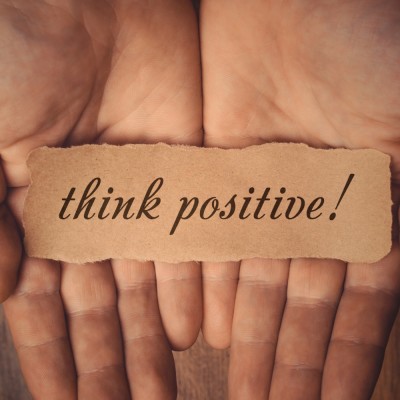 person holding a piece of paper that says think positive