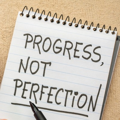 piece of paper that reads progress over perfection